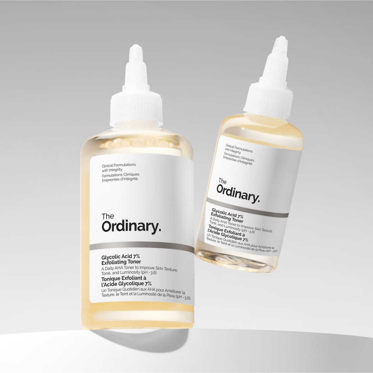 Two bottles of 'The Ordinary' toner on a gray background